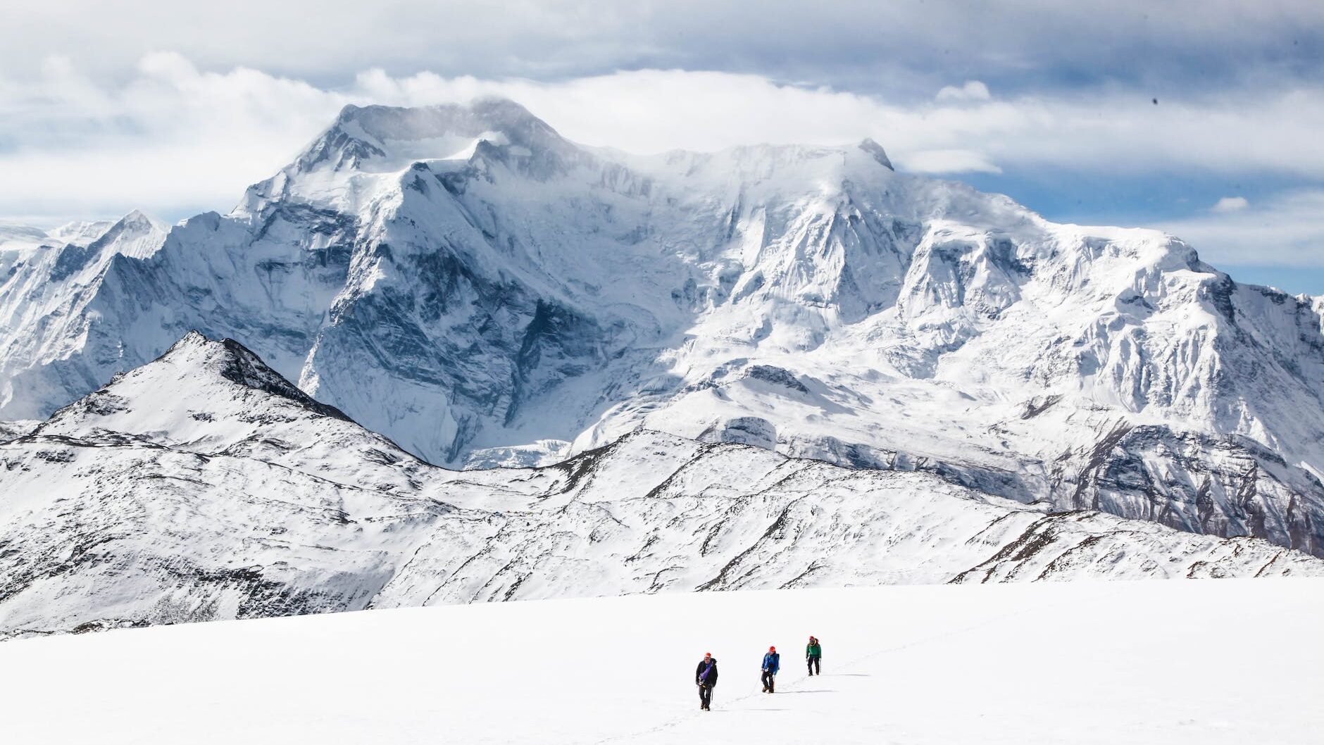 unrecognizable people walking near mountain on snowy terrain
